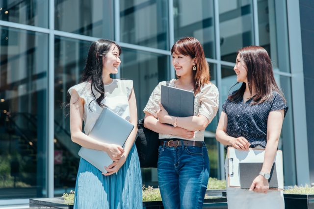 ノートPCを持って笑いあっている3人の女性のイメージ